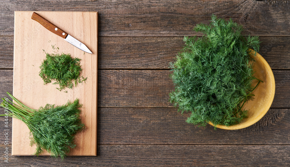fresh dill in a wooden bowl on the table, top view, rustic style. fresh dill in a wooden bowl on the table, top view, rustic style.