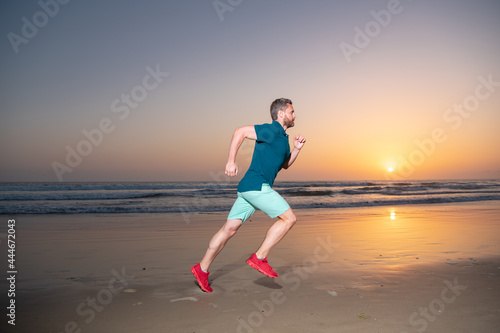 Full length of healthy man running and sprinting outdoors. Male runner. Fit male fitness runner during sunset workout.