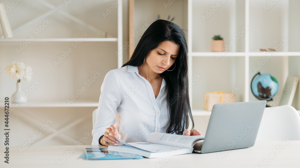 Online courses. Remote education. Home studying Book research. Concentrated student girl reading preparing for exam at light cozy room. Online courses. Remote education. Home studying Book research. Concentrated student girl reading preparing for exam at light cozy room.