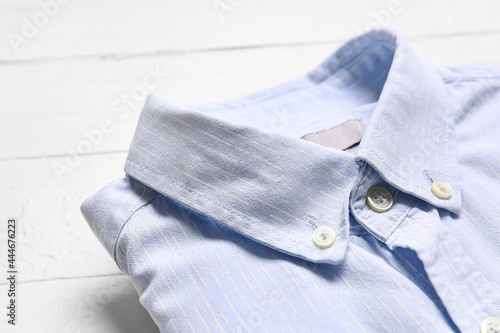 Stylish male shirt on light wooden background, closeup