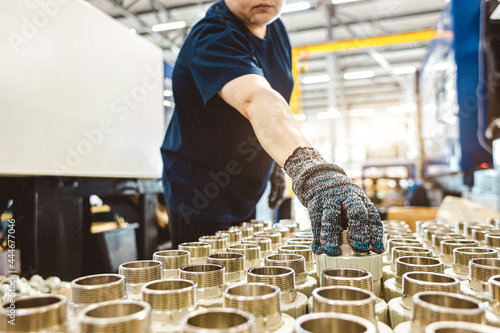 male worker checks many metal pipe couplings in a pipe factory