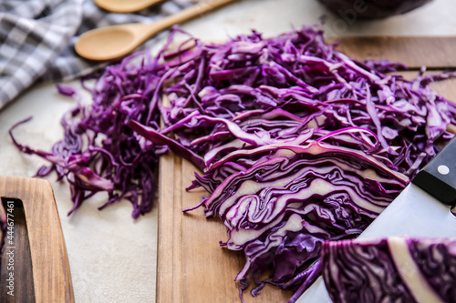 Board with cut fresh purple cabbage on light background, closeup