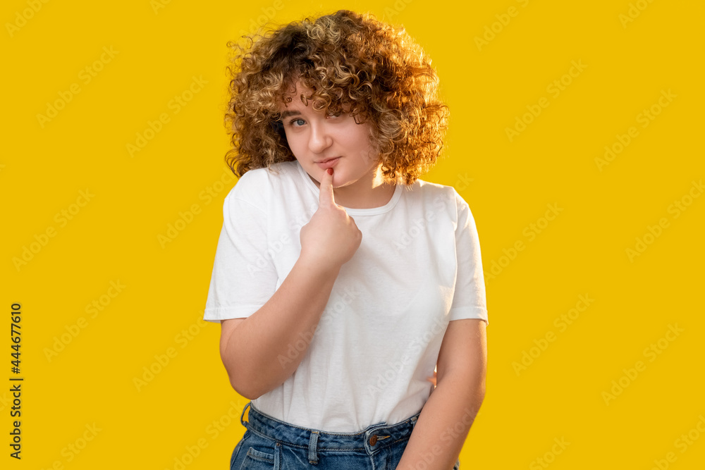 Shy woman. Plus size beauty. Pleasant compliment. Body positive. Flattered smiling overweight girl with curly hair casual style isolated on yellow. Shy woman. Plus size beauty. Pleasant compliment. Body positive. Flattered smiling overweight girl with curly hair casual style isolated on yellow.