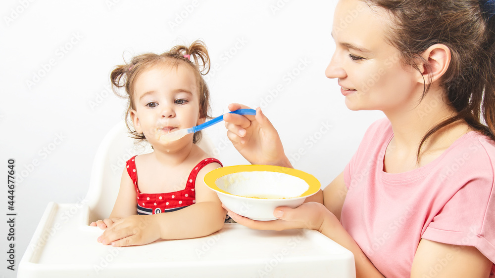 Young nanny feeding cute little baby at home Young nanny feeding cute little baby at home