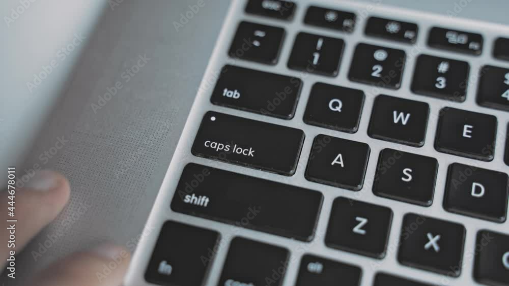Man hand finger pushes one time caps lock key button on laptop keyboard Man hand finger pushes one time caps lock key button on laptop keyboard