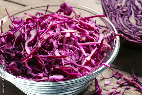 Bowl with cut fresh purple cabbage on wooden background, closeup