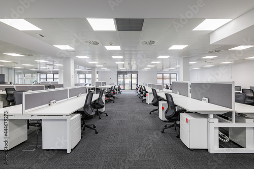 Modern corporate open office in minimalist modern design in whites and greys, empty office workstations.