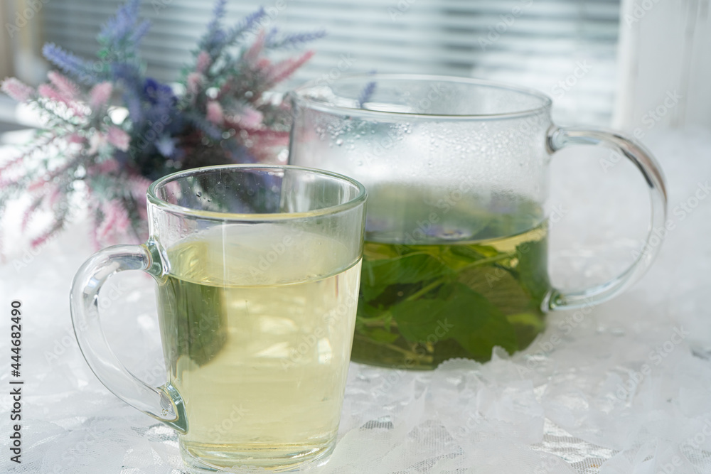 In a glass mug and teapot Fresh, floral, herbal tea made from mint and currant leaves in a mug. In a glass mug and teapot Fresh, floral, herbal tea made from mint and currant leaves in a mug.