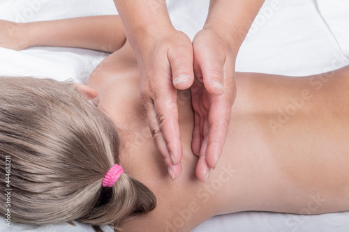 A teenage girl with white hair is lying on her stomach. A professional doctor does a back massage. Close-up.