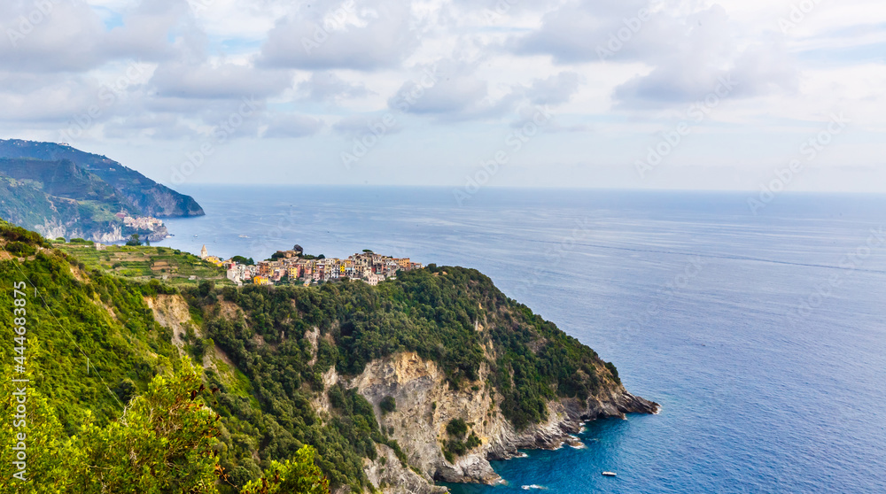 Fishing boats moored on water in harbor of Ligurian and Mediterranean Sea near coastline of Riviera di Levante of National park Cinque Terre Coast with blue sky, Riomaggiore village, Liguria, Italy.
