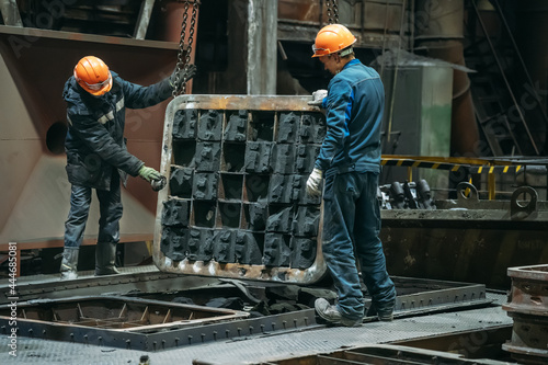 Unrecognizable workers with molds for metal cast in metallurgical plant foundry. Heavy industry.