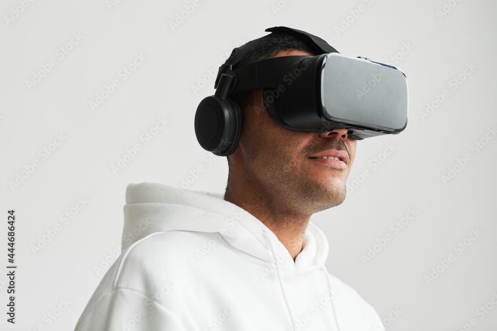 Minimal portrait of modern man wearing VR headset against white background, copy space Minimal portrait of modern man wearing VR headset against white background, copy space