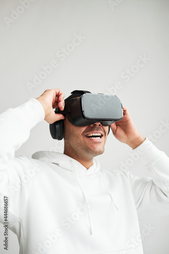 Minimal vertical portrait of emotional young man wearing VR headset against white background, copy space