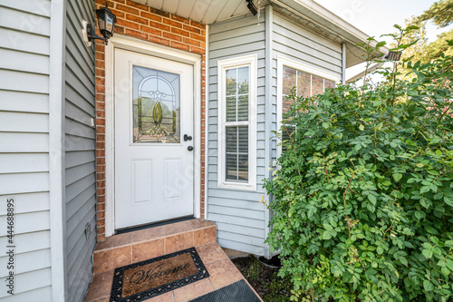 Front door exterior with bricks and vinyl siding wall