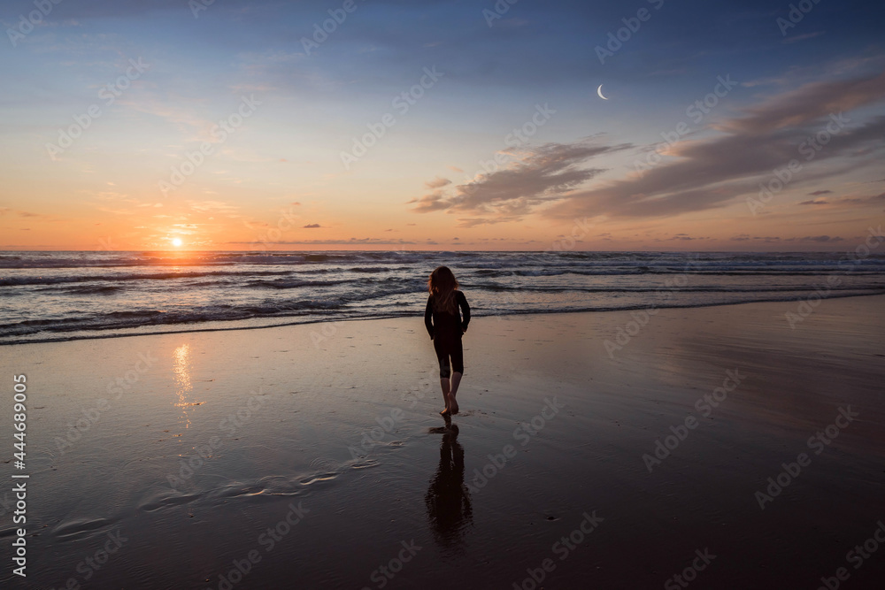 young girl walking alone on the beach at sunset
