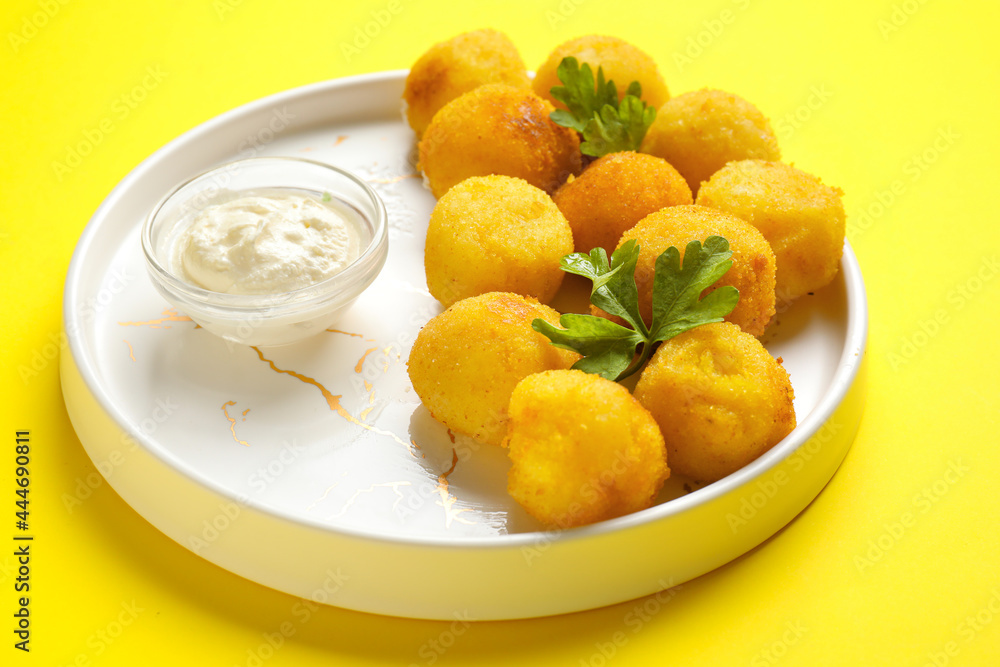 Plate with fried potato balls and sauce on color background Plate with fried potato balls and sauce on color background