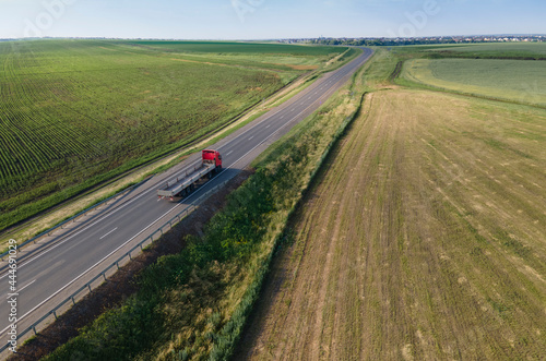 Red tipper truck on street road highway transportation. Semi-truck countryside aerial view.