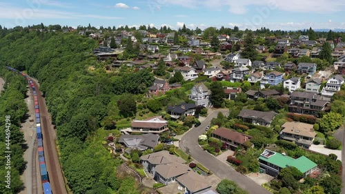 Cinematic 4K aerial drone footage of moving train cars in Sunset Hill near Loyal Heights, Adams, Lawtonwood, Shilshole Bay Marina, Ballard, affluent suburbs of Seattle by the Puget Sound photo