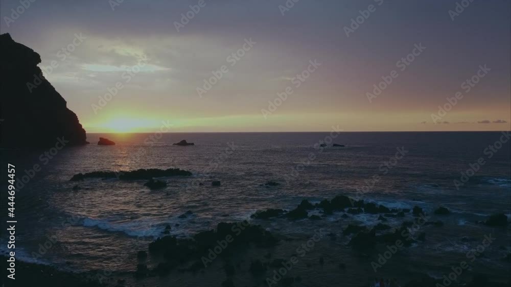 Glowing orange sunset horizon over rocky ocean beachfront coastline rising aerial view Glowing orange sunset horizon over rocky ocean beachfront coastline rising aerial view