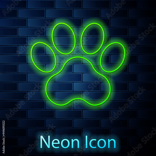 Glowing neon line Paw print icon isolated on brick wall background. Dog or cat paw print. Animal track. Vector