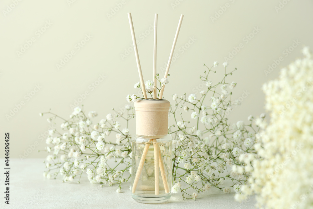 Diffuser and flowers on white textured table Diffuser and flowers on white textured table