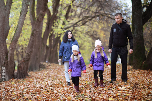 Young family on a walk in the autumn park on a sunny day. Happiness to be together.