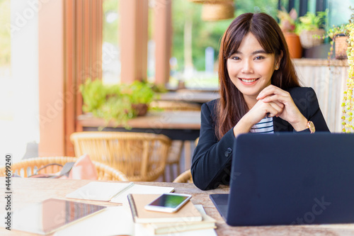 Young attractive business woman in her casual suit working on her computer at outdoor patio of her office, working mobile or young entrepreneur concept