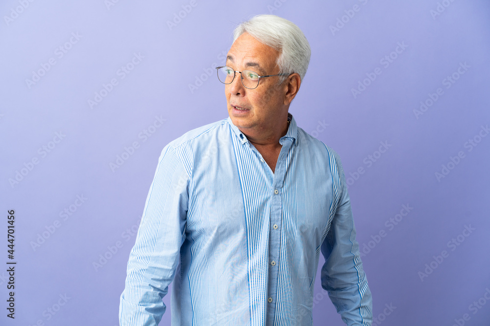 Middle age Brazilian man isolated on purple background doing surprise gesture while looking to the side Middle age Brazilian man isolated on purple background doing surprise gesture while looking to the side