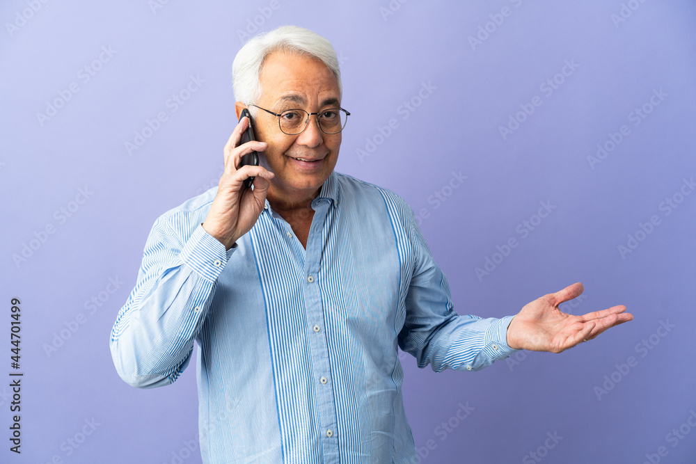 Middle age Brazilian man isolated on purple background keeping a conversation with the mobile phone with someone Middle age Brazilian man isolated on purple background keeping a conversation with the mobile phone with someone