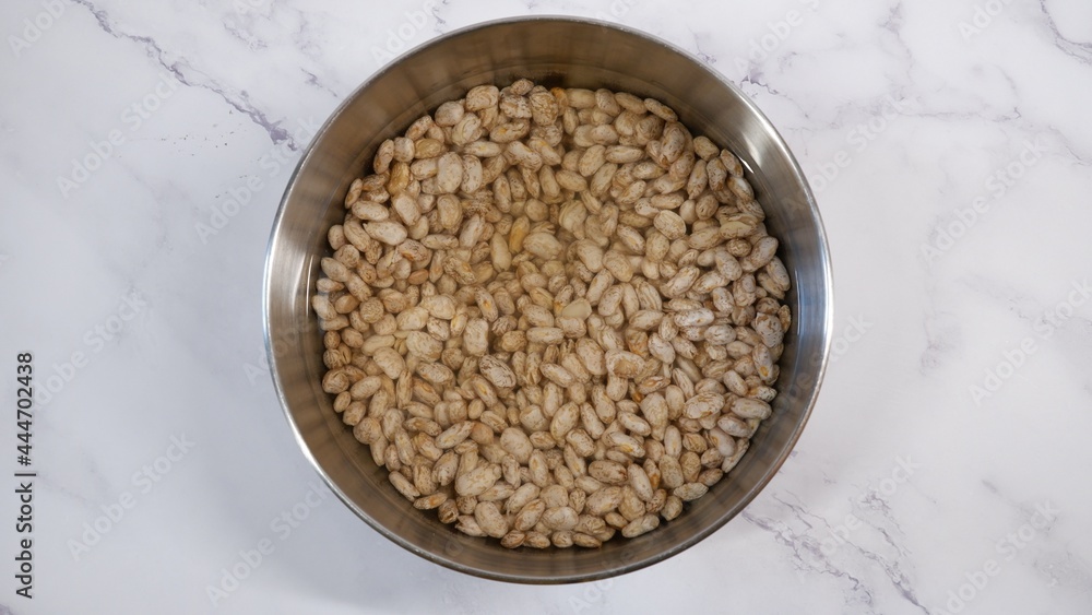 white pinto beans to soak in water in a stainless steel bowl white pinto beans to soak in water in a stainless steel bowl