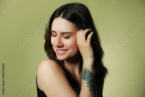 Beautiful young woman with nose piercing on green background