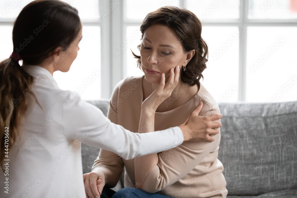 Loving young adult daughter touch caress support unhappy sad old Caucasian mother feeling distressed depressed at home. Supportive grownup girl comfort upset middle-aged mom mourning yearning. Loving young adult daughter touch caress support unhappy sad old Caucasian mother feeling distressed depressed at home. Supportive grownup girl comfort upset middle-aged mom mourning yearning.