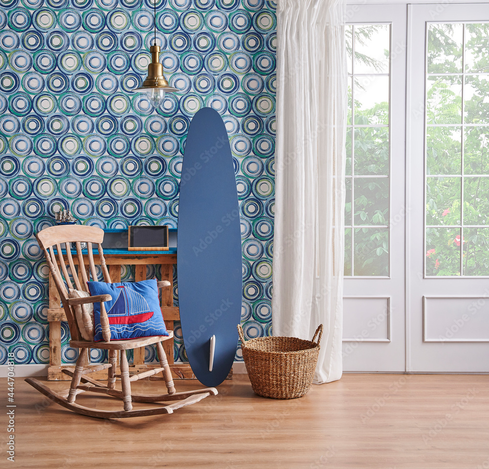 Modern living room, blue wallpaper, decorative wooden palette bookshelf,  surfboard style,wood rocking chair, gold lamp vase of green plant and home  accessory. Photos | Adobe Stock