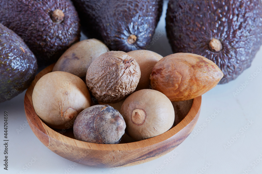 Obraz premium Avocado seed in a wooden bowl on white background, for medicinal use