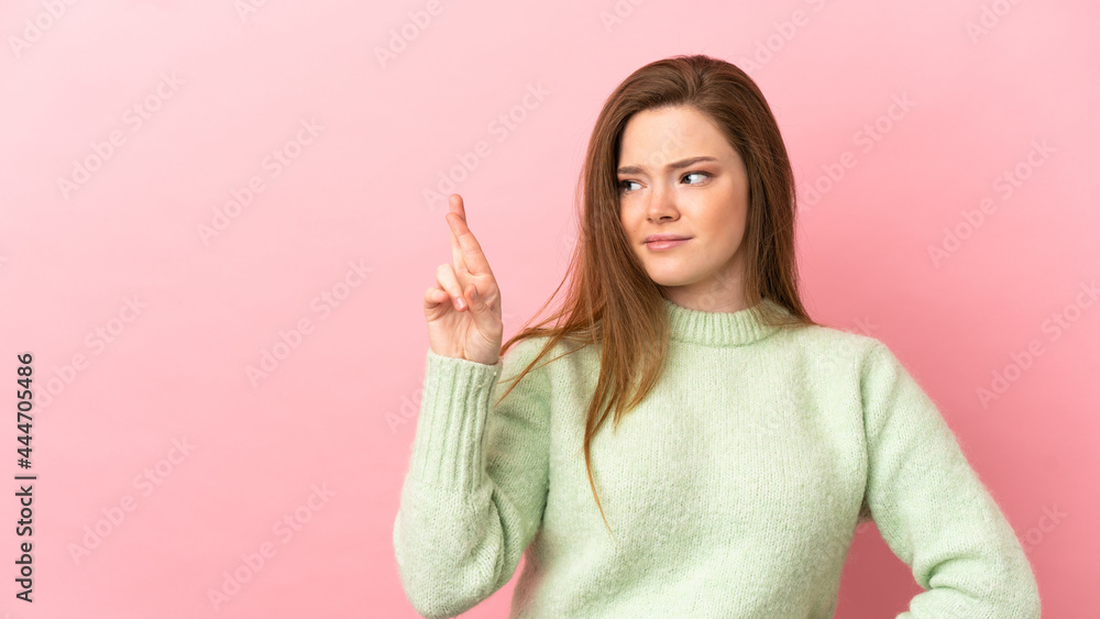 Teenager girl over isolated pink background with fingers crossing and wishing the best Teenager girl over isolated pink background with fingers crossing and wishing the best