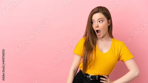 Teenager girl over isolated pink background doing surprise gesture while looking to the side