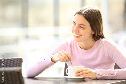 Happy woman stirring coffee in a restaurant photo