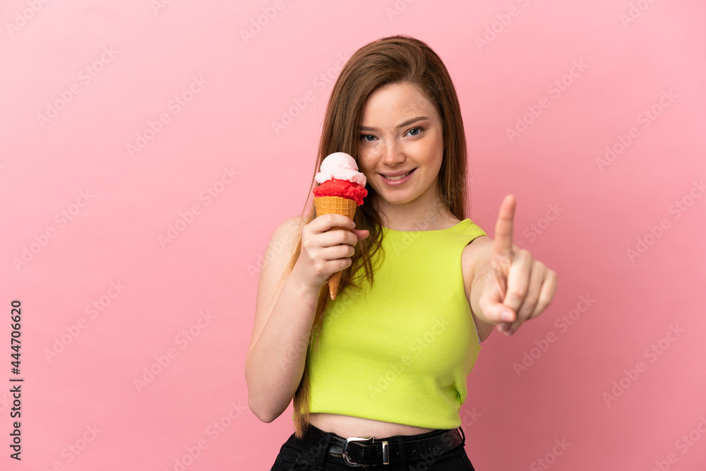 Teenager girl with a cornet ice cream over isolated pink background showing and lifting a finger Teenager girl with a cornet ice cream over isolated pink background showing and lifting a finger