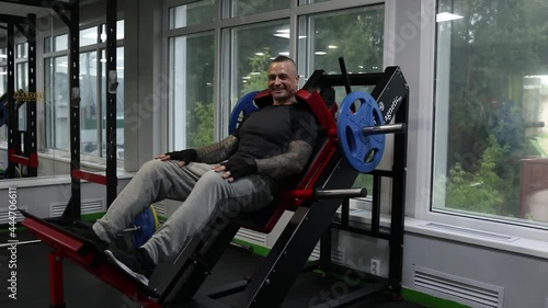 A man in sportswear with tattoos and a shaved head says something on the Gakk machine simulator