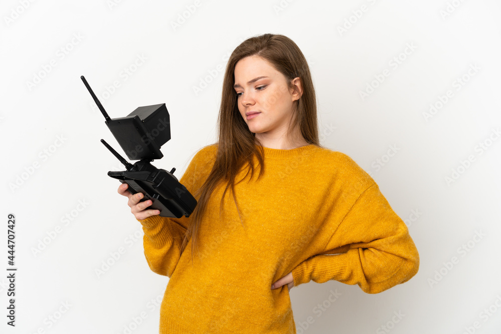 Teenager girl holding a drone remote control over isolated white background suffering from backache for having made an effort Teenager girl holding a drone remote control over isolated white background suffering from backache for having made an effort