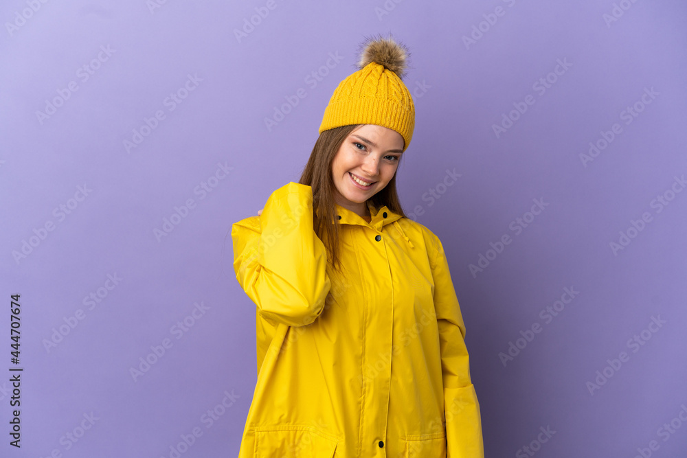 Teenager girl wearing a rainproof coat over isolated purple background laughing Teenager girl wearing a rainproof coat over isolated purple background laughing