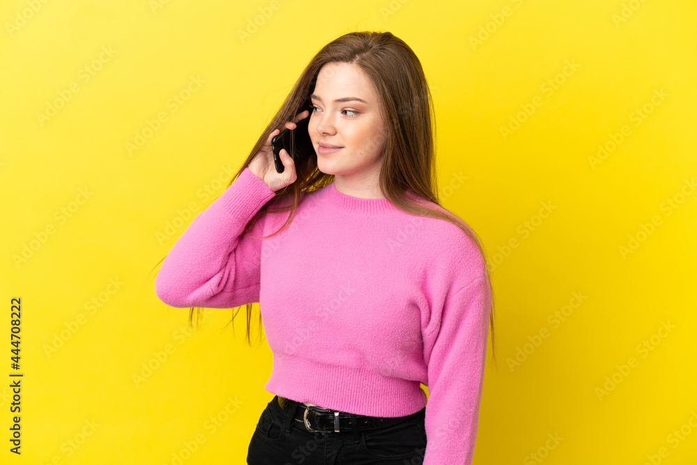 Teenager girl using mobile phone over isolated yellow background looking side Teenager girl using mobile phone over isolated yellow background looking side