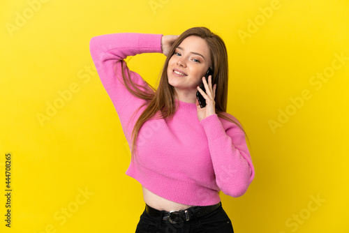 Teenager girl using mobile phone over isolated yellow background smiling a lot © luismolinero