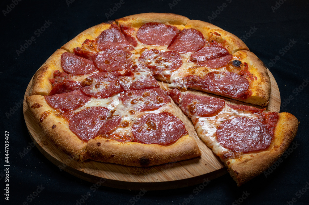 Pizza with tomato sauce, mozzarella and salami on a black background. Pizza with tomato sauce, mozzarella and salami on a black background.