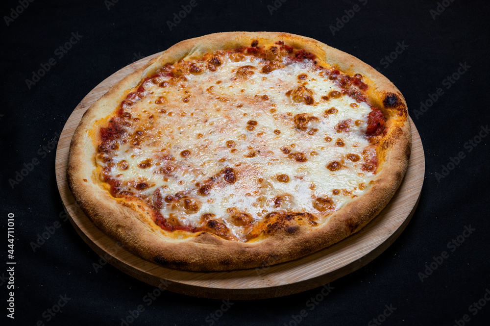 Pizza with tomato sauce and mozzarella cheese on a black background. Pizza with tomato sauce and mozzarella cheese on a black background.