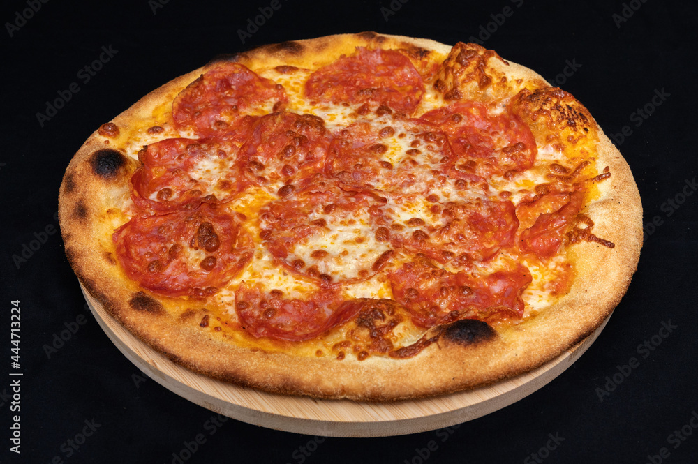Pizza with tomato sauce, mozzarella and spicy salami on black fudal.