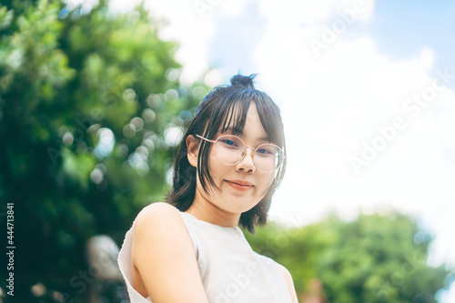 Portrait of young adult asian woman face wear eyeglasses and short hair stay at home in green garden yard on day.