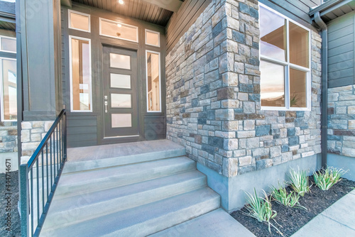 Home facade with stone brick wall and gray front door with frosted glass panels