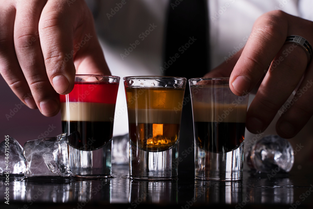 Barman preparing cocktail shots at the bar counter. Barman mixing drinks at the night club...