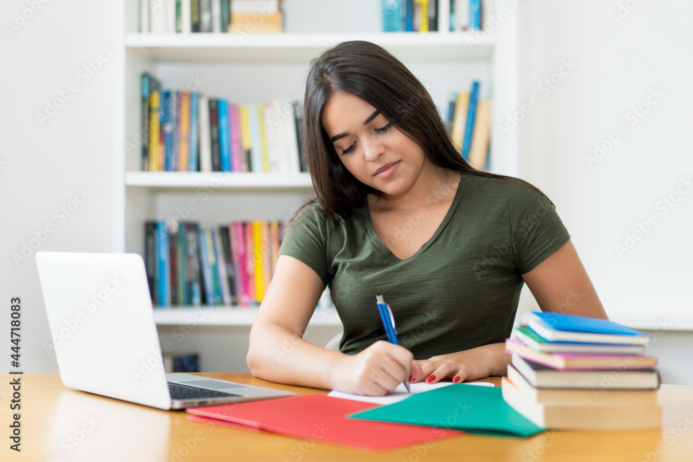 Young spanish female student writing notes at desk Young spanish female student writing notes at desk